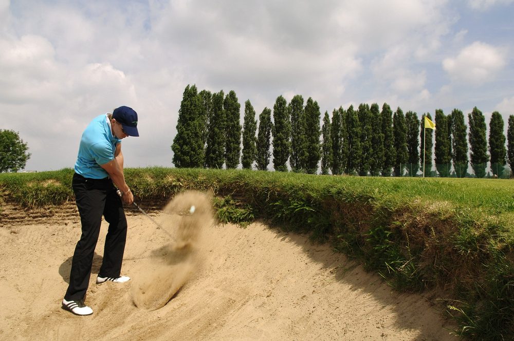 Golfista saliendo de un bunker de arena